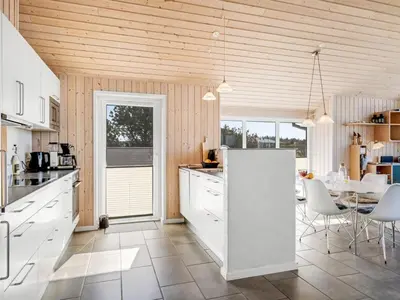 a kitchen with a white refrigerator and a table at Holiday Home Hornbogi - 300m from the sea by Interhome in Torsted