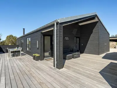 a black modular building with a wooden deck at Holiday Home Helli - 650m from the sea by Interhome in Torsted