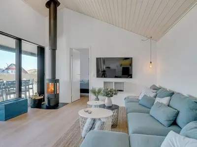 a living room with a blue couch and a fireplace at Holiday Home Aiko - 50m from the sea by Interhome in Torsted