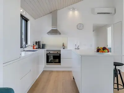 a white kitchen with white cabinets and a sink at Holiday Home Aiko - 50m from the sea by Interhome in Torsted