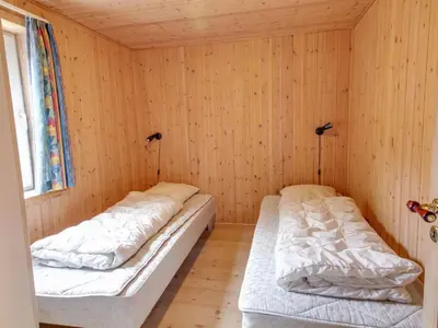 two beds in a room with wooden walls at Holiday Home Konrad - 400m from the sea by Interhome in Torsted