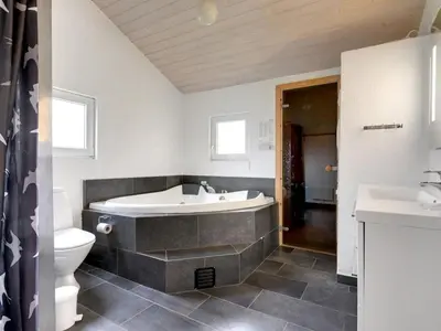 a bathroom with a tub and a toilet and a sink at Holiday Home Ritte - 200m from the sea by Interhome in Torsted
