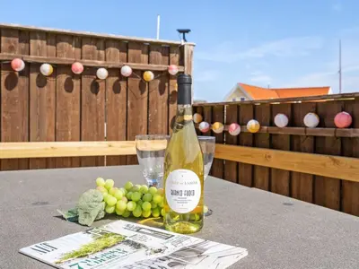 a bottle of wine and grapes on a table at Holiday Home Bernice - 150m from the sea by Interhome in Torsted