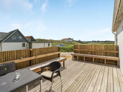 a deck with wooden benches and a table and chairs at Holiday Home Bernice - 150m from the sea by Interhome in Torsted