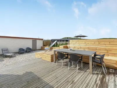 a patio with a table and chairs on a wooden deck at Holiday Home Bernice - 150m from the sea by Interhome in Torsted