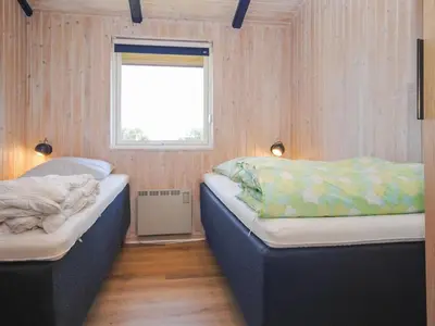 two beds in a room with wooden walls and a window at Holiday Home Jerrik - 900m from the sea by Interhome in Torsted