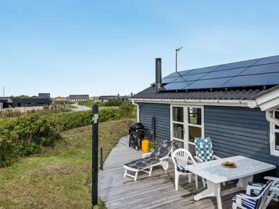 a blue house with a table and chairs on a deck at Holiday Home Adisl - 350m from the sea by Interhome in Torsted