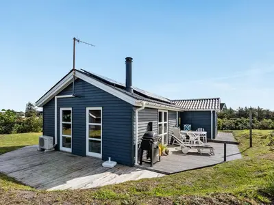 a blue tiny house with a large wooden deck at Holiday Home Adisl - 350m from the sea by Interhome in Torsted