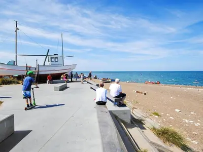 a group of people sitting on a sidewalk near the beach at Holiday Home Adisl - 350m from the sea by Interhome in Torsted