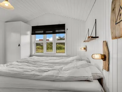 a white bed in a white room with a window at Holiday Home Adisl - 350m from the sea by Interhome in Torsted