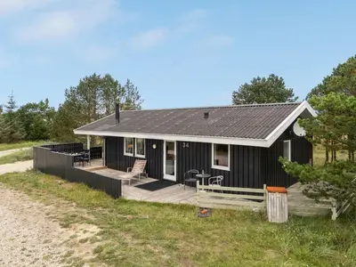 a black house with a deck on the beach at Holiday Home Mads - 950m from the sea by Interhome in Torsted