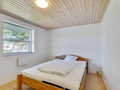 a bedroom with a bed with a wooden ceiling at Holiday Home Örjan - 400m from the sea by Interhome in Torsted