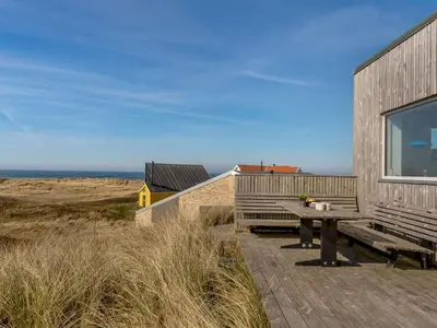 a wooden deck with a picnic table next to a building at Holiday Home Ginne - 125m from the sea by Interhome in Torsted