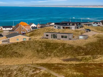 a group of houses on a hill next to the ocean at Holiday Home Ginne - 125m from the sea by Interhome in Torsted