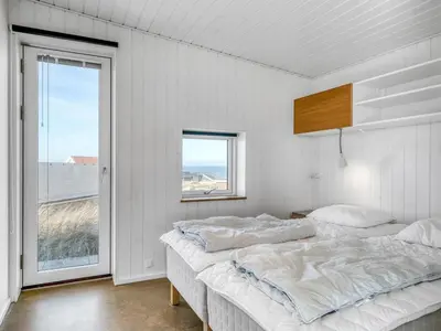 a white bedroom with two beds and a window at Holiday Home Ginne - 125m from the sea by Interhome in Torsted