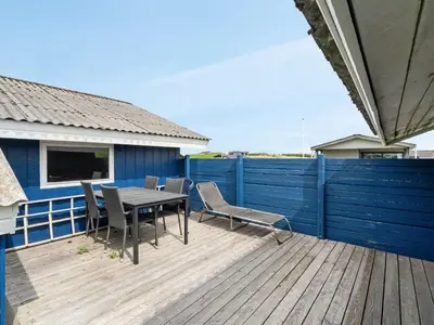 a deck with a table and chairs and a blue fence at Holiday Home Joern - 300m from the sea by Interhome in Torsted