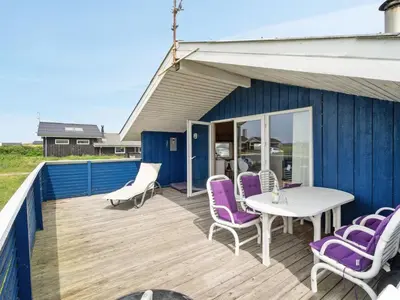 a wooden deck with purple chairs and a white table at Holiday Home Joern - 300m from the sea by Interhome in Torsted