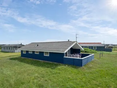 a blue house with chairs in a field at Holiday Home Joern - 300m from the sea by Interhome in Torsted