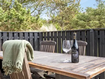 a wooden table with a bottle of wine and a glass at Holiday Home Fridolina - 200m from the sea by Interhome in Torsted