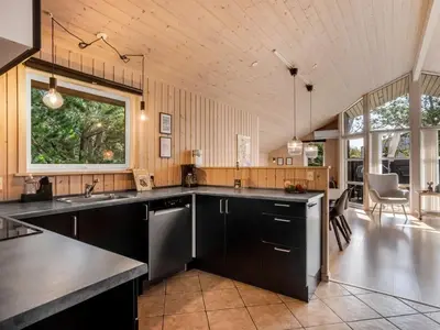 a large kitchen with black cabinets and a large window at Holiday Home Ansfried - 900m from the sea by Interhome in Torsted