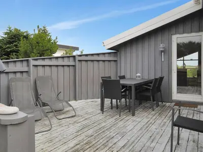 a patio with a table and chairs on a deck at Holiday Home Dode - 225m from the sea by Interhome in Torsted