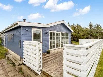 a blue tiny house with a wooden deck at Holiday Home Kanerva - 350m from the sea by Interhome in Torsted