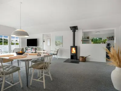 a living room with a table and a fireplace at Holiday Home Kanerva - 350m from the sea by Interhome in Torsted