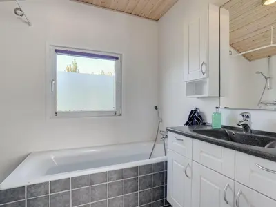 a bathroom with a bath tub and a sink at Holiday Home Kanerva - 350m from the sea by Interhome in Torsted