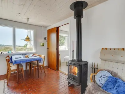 a living room with a stove and a table with chairs at Holiday Home Letta - 800m from the sea by Interhome in Torsted