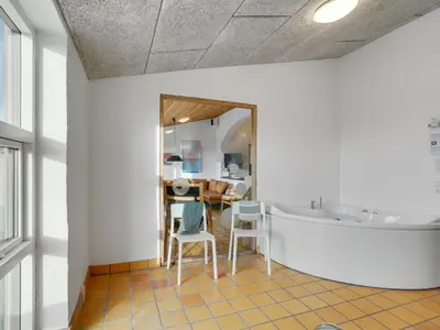a bathroom with a tub and a table and chairs at Holiday Home Teijo - 400m from the sea by Interhome in Torsted