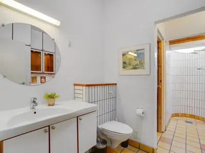 a bathroom with a sink and a toilet and a mirror at Holiday Home Teijo - 400m from the sea by Interhome in Torsted