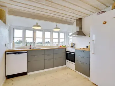 a kitchen with gray cabinets and a white refrigerator at Holiday Home Meindor - 350m from the sea by Interhome in Torsted