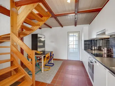a kitchen with a table and a staircase in a room at Apartment Nermin - 300m from the sea by Interhome in Torsted