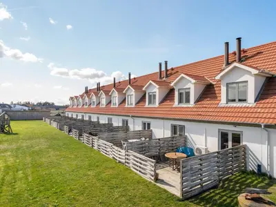 a row of white buildings with a grass yard at Apartment Nermin - 300m from the sea by Interhome in Torsted