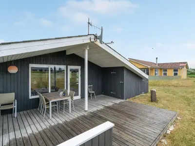 a deck with a table and chairs on a house at Holiday Home Svea - 400m from the sea by Interhome in Torsted
