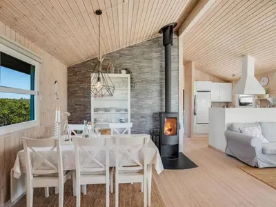 a dining room and living room with a table and a fireplace at Holiday Home Abel - 350m from the sea by Interhome in Løkken