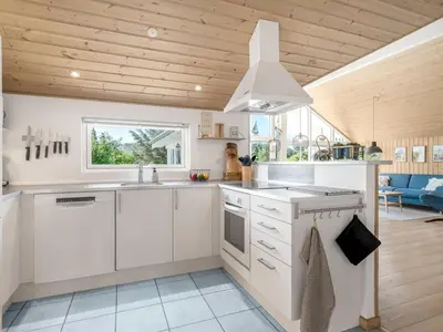 a kitchen with white cabinets and a wooden ceiling at Holiday Home Federica - 500m from the sea by Interhome in Løkken