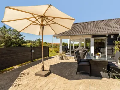 a patio with a table and an umbrella at Holiday Home Federica - 500m from the sea by Interhome in Løkken