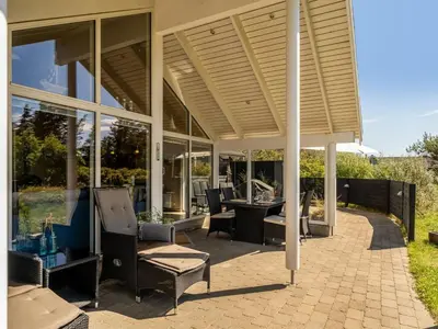 a covered patio with chairs and a table at Holiday Home Federica - 500m from the sea by Interhome in Løkken