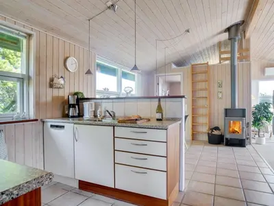 a kitchen with white cabinets and a fireplace at Holiday Home Elsabet - 750m from the sea by Interhome in Løkken