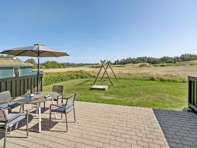 a patio with a table and chairs and an umbrella at Holiday Home Elsabet - 750m from the sea by Interhome in Løkken