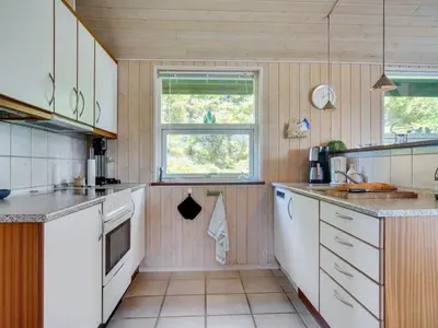 a kitchen with white cabinets and a window at Holiday Home Elsabet - 750m from the sea by Interhome in Løkken