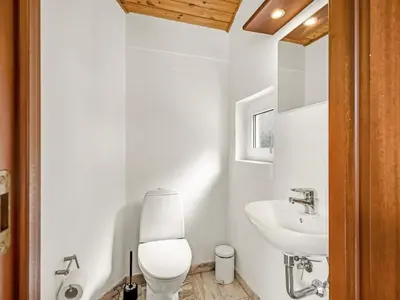 a white bathroom with a toilet and a sink at Holiday Home Sunneva - 1km from the sea by Interhome in Løkken