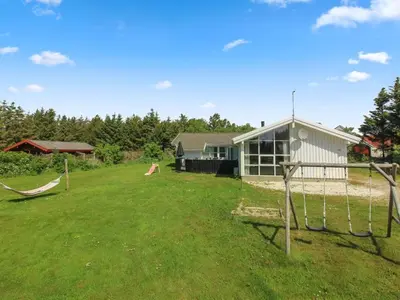 a yard with swings in front of a house at Holiday Home Panu - 600m from the sea by Interhome in Løkken