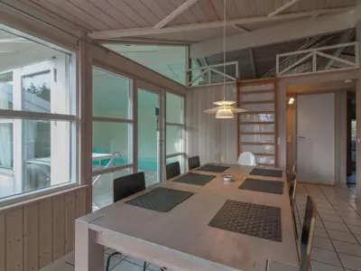 a dining room with a large wooden table and windows at Holiday Home Panu - 600m from the sea by Interhome in Løkken
