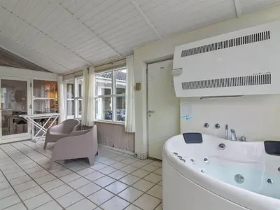 a bathroom with a tub and a chair and a table at Holiday Home Panu - 600m from the sea by Interhome in Løkken
