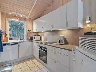 a white kitchen with white cabinets and a window at Holiday Home Panu - 600m from the sea by Interhome in Løkken