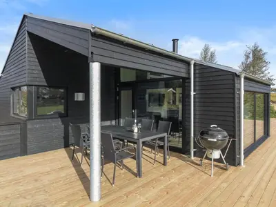 a black house with a table and a grill on a deck at Holiday Home Vanamo - 300m from the sea by Interhome in Løkken