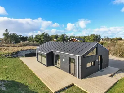a house with a black roof on a deck at Holiday Home Vanamo - 300m from the sea by Interhome in Løkken