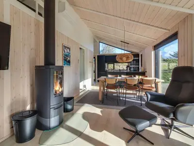 a living room with a fireplace and a dining room at Holiday Home Vanamo - 300m from the sea by Interhome in Løkken